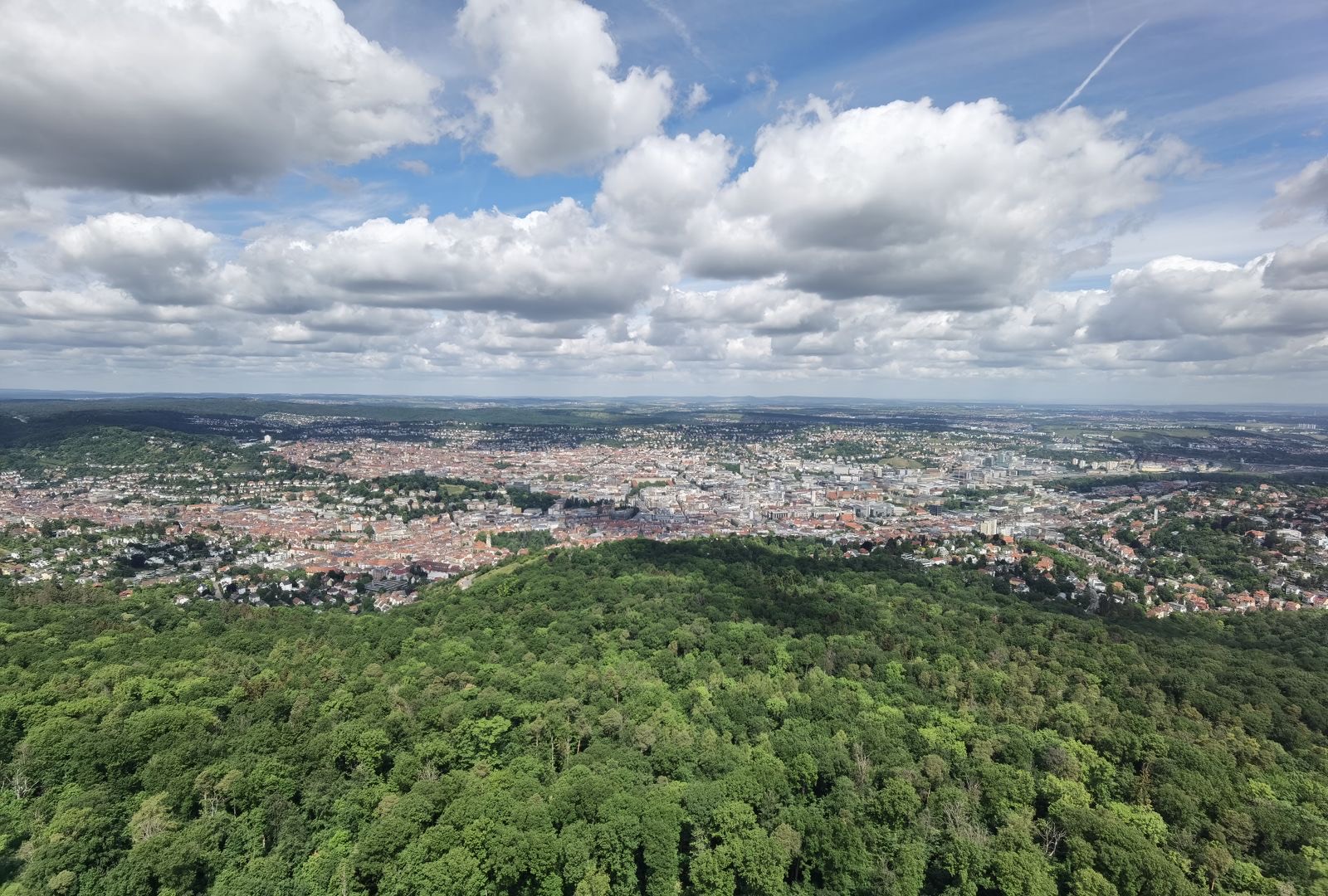 A town nestled among green forested hills under a clear blue sky